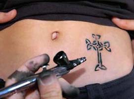 A cross tattoo on a young womans belly